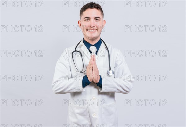 Smiling latin doctor with palms together isolated. Cheerful doctor putting palms together. Handsome doctor with hands together isolated
