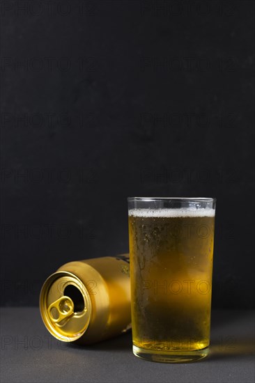 Front view beer can beside glass with beer