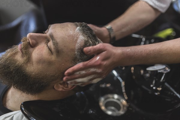 Crop hairdresser washing hair client