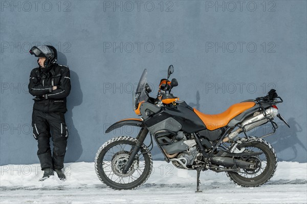 Man standing beside motorcycle with helmet
