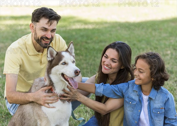 Smiley boy parents petting dog while park