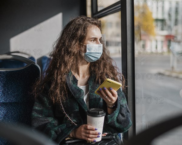 Woman with curly hair holding mobile phone coffee