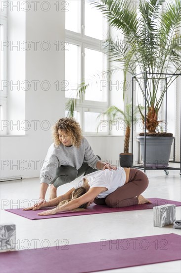 Teacher helping woman stretch