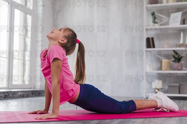 Side view girl exercising pink exercise mat