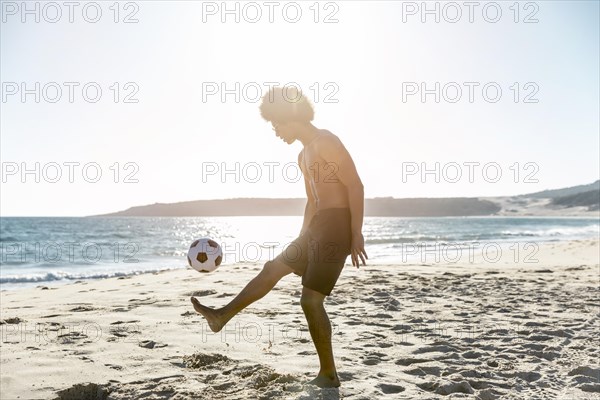 Young sportsman tossing up ball seacoast