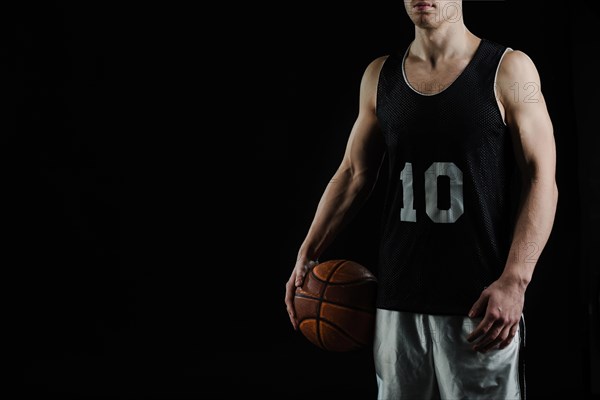 Professional basketball player holding ball his arm