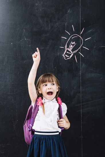 Cute pupil pointing up blackboard