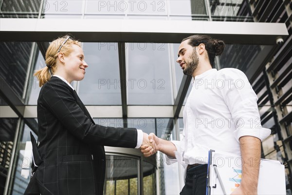 Low angle view businessman businesswoman shaking each other hands