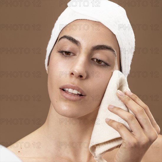 Young woman touching her face with towel