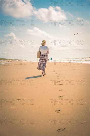 Tourist barefoot with skirt on sandy beach