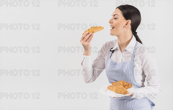 Confectioner woman tasting croissant