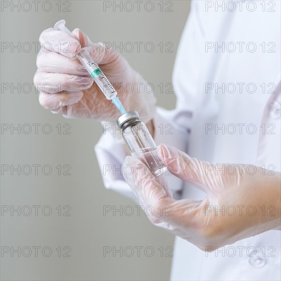 Side view female researcher with gloves holding syringe