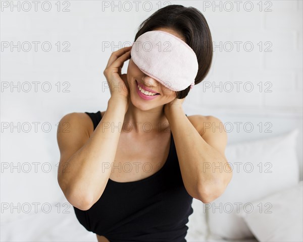 Smiley woman putting sleeping mask