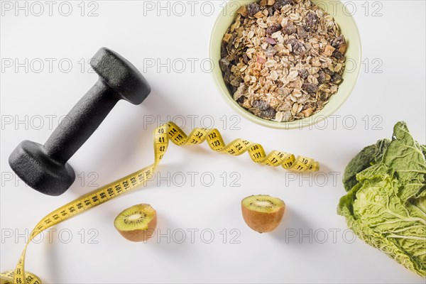 Diet food with dumbbell measuring tape white background