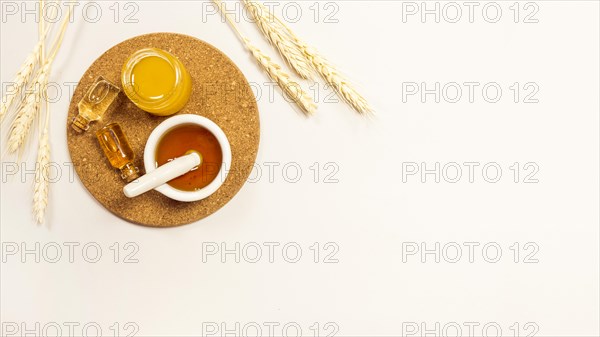 Essential oil honey brown cork with wheat ears against white backdrop