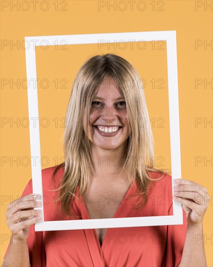 Young smiling woman holding white border frame front her face