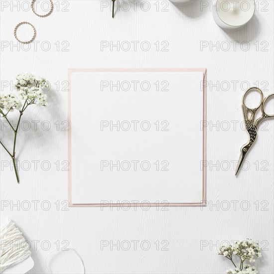 Blank white paper surrounded with rings gypsophila string candles scissor white background