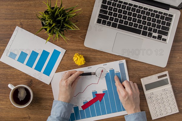 Top view office desk with laptop growth chart analyzed by hands