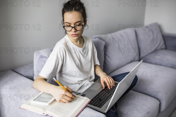 Woman with laptop making notes book