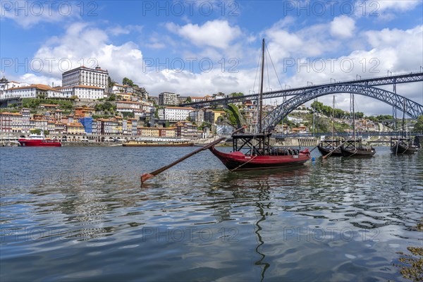 View over the traditional Rabelo boats on the Douro riverbank in Vila Nova de Gaia towards the old town of Porto and the bridge Ponte Dom Luis I