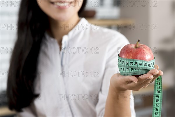 Close up woman s hand holding red apple with green measurement tape