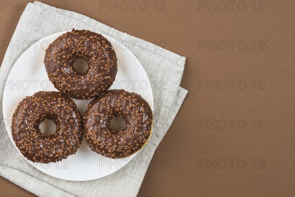 Chocolate glazed doughnuts white plate gray cloth