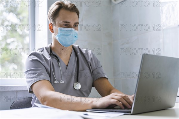Doctor with stethoscope medical mask working laptop