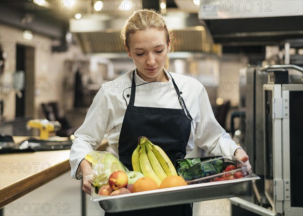 Female chef holding tray with fruit