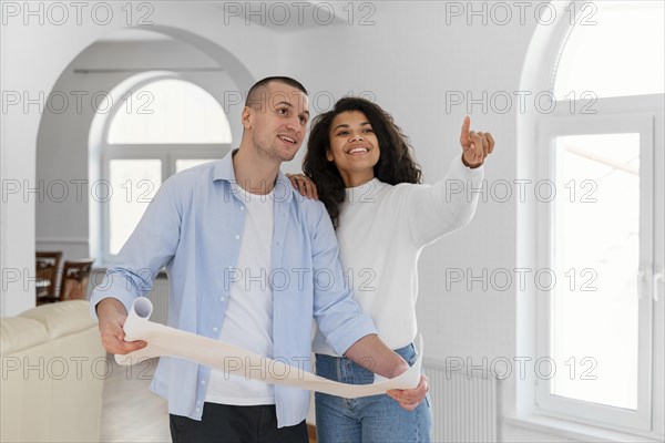 Smiley couple holding house plans
