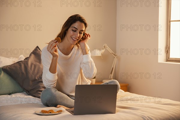 Front view woman using laptop home talking phone