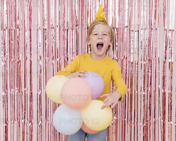 Medium shot boy holding colorful balloons