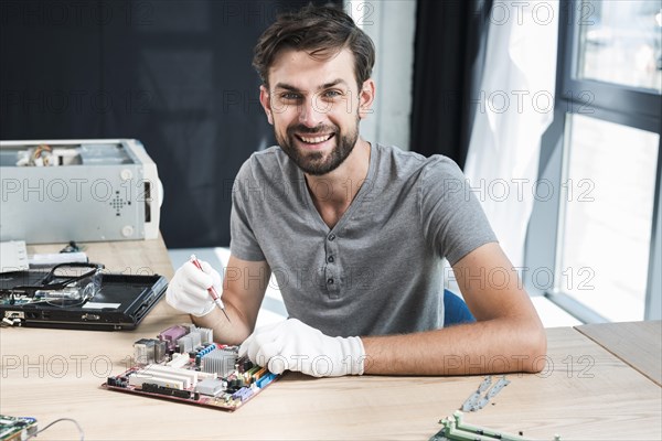 Portrait smiling male technician working computer motherboard