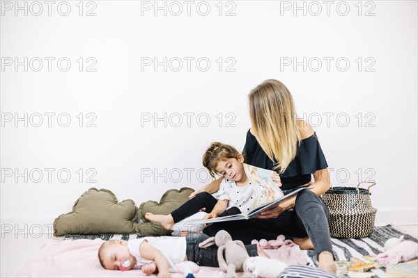 Woman girl reading book near baby