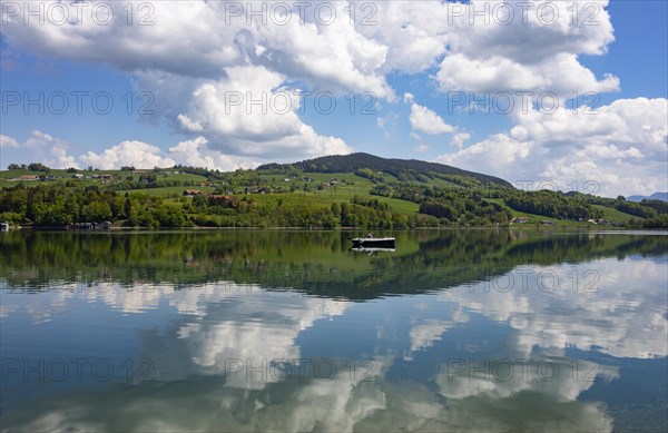 (Cumulus) clouds with fishing boat reflected in the Irrsee, Zell am moss, Salzkammergut, Upper Austria, Austria, Europe