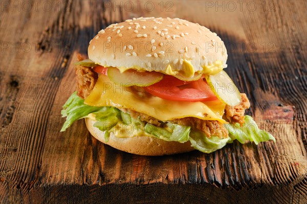 Chicken cheeseburger with fresh and pickled vegetables on wooden background