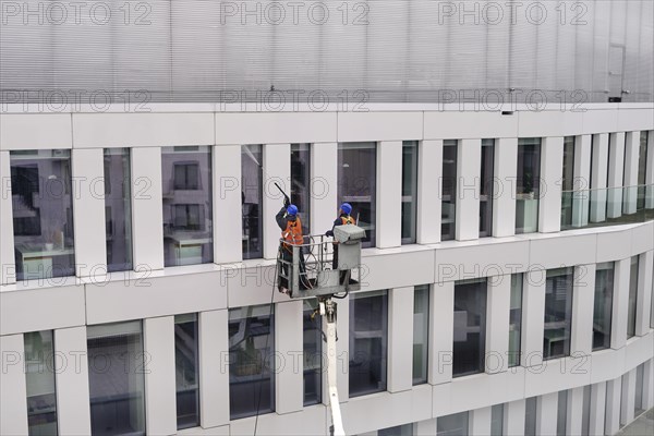 Two workers wearing safety harness wash walls