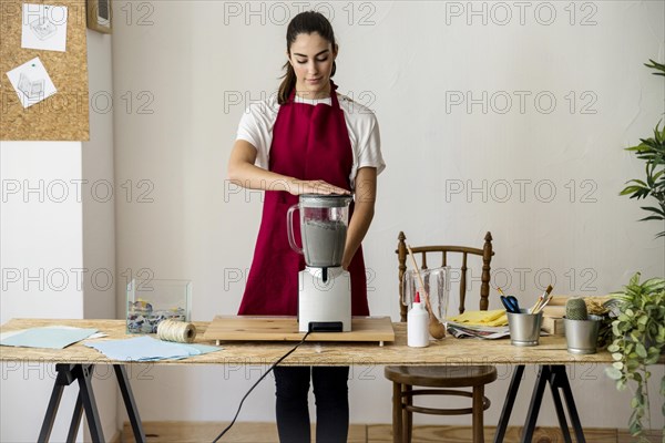 Young woman preparing paper pulp mixer workshop