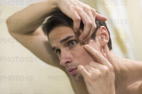 Portrait man popping pimple