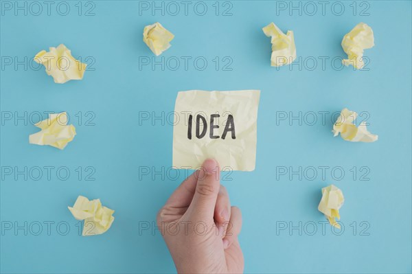 Close up person holding idea paper with crumpled ball papers blue backdrop
