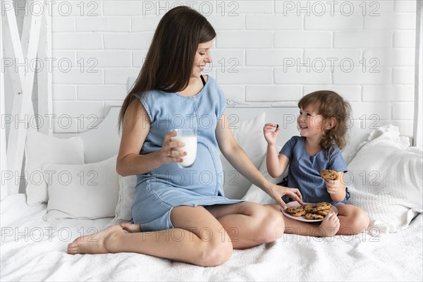 Long shot mother daughter eating chocolate cookies