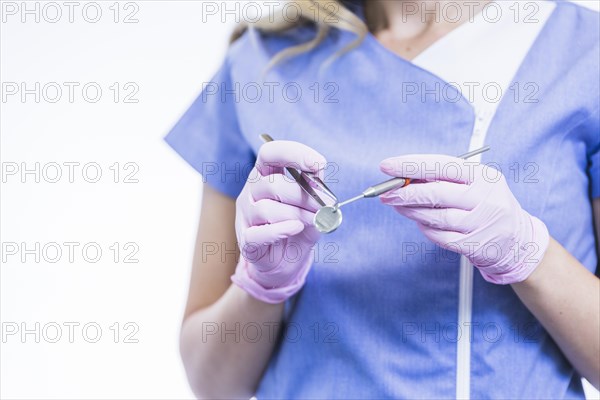 Midsection view female dentist s hand holding dental instruments
