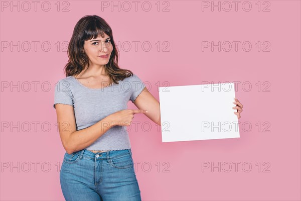 Beautiful woman pointing at a blank whiteboard against a pink background