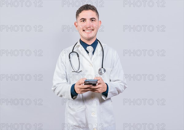 Happy latin doctor holding phone isolated. Cheerful doctor using cellphone looking at camera isolated