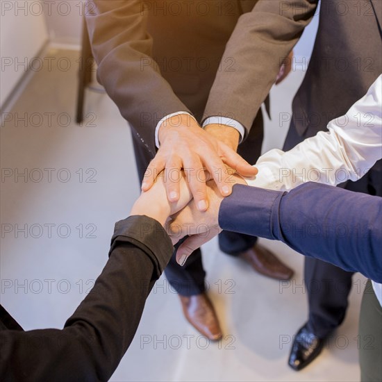 Close up businesspeople stacking hands meeting office