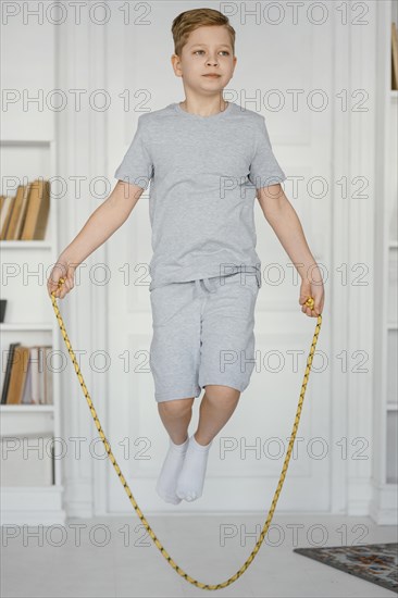 Full shot boy jumping rope indoors