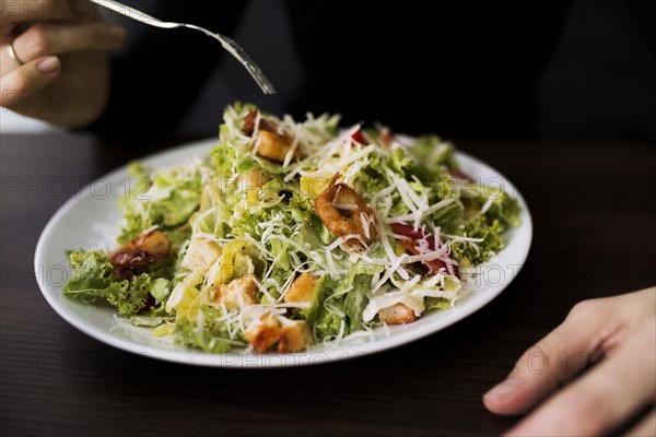 Person eating tasty caesar salad with croutons restaurant