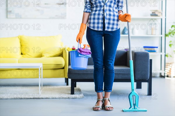 Female janitor holding cleaning equipments home
