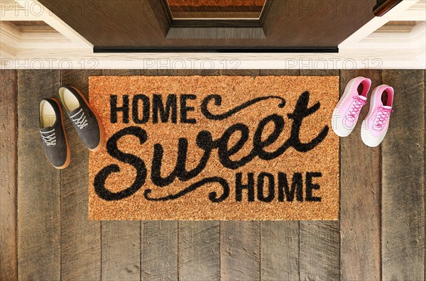 Home sweet home doormat with man and woman shoes on the porch at the front door
