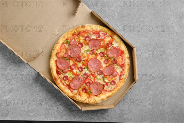 Top view of pizza with sausage and colorful bell pepper in cardboard box