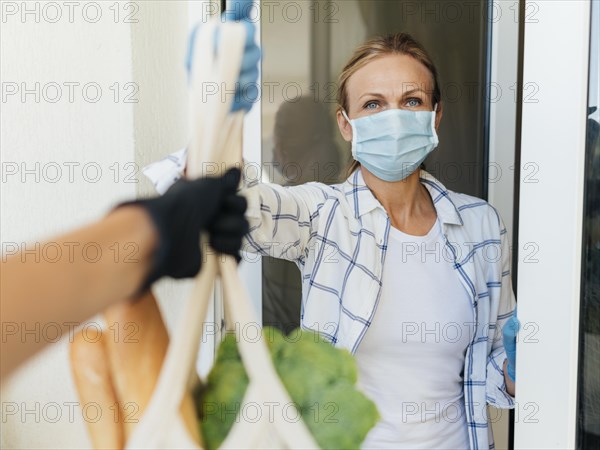 Woman with medical mask home picking up her groceries self isolation